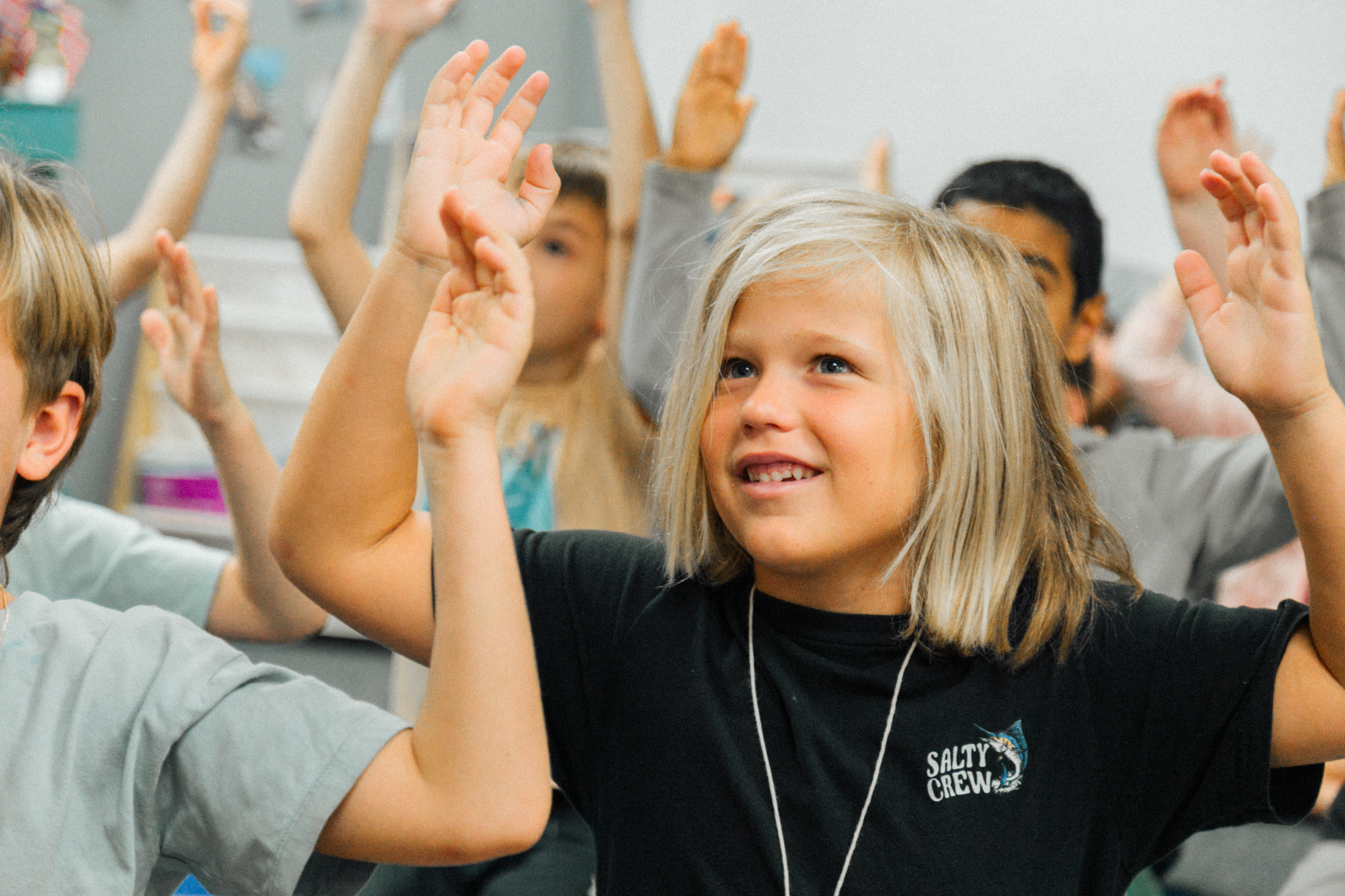 Students with their hands raised in a Thrive classroom