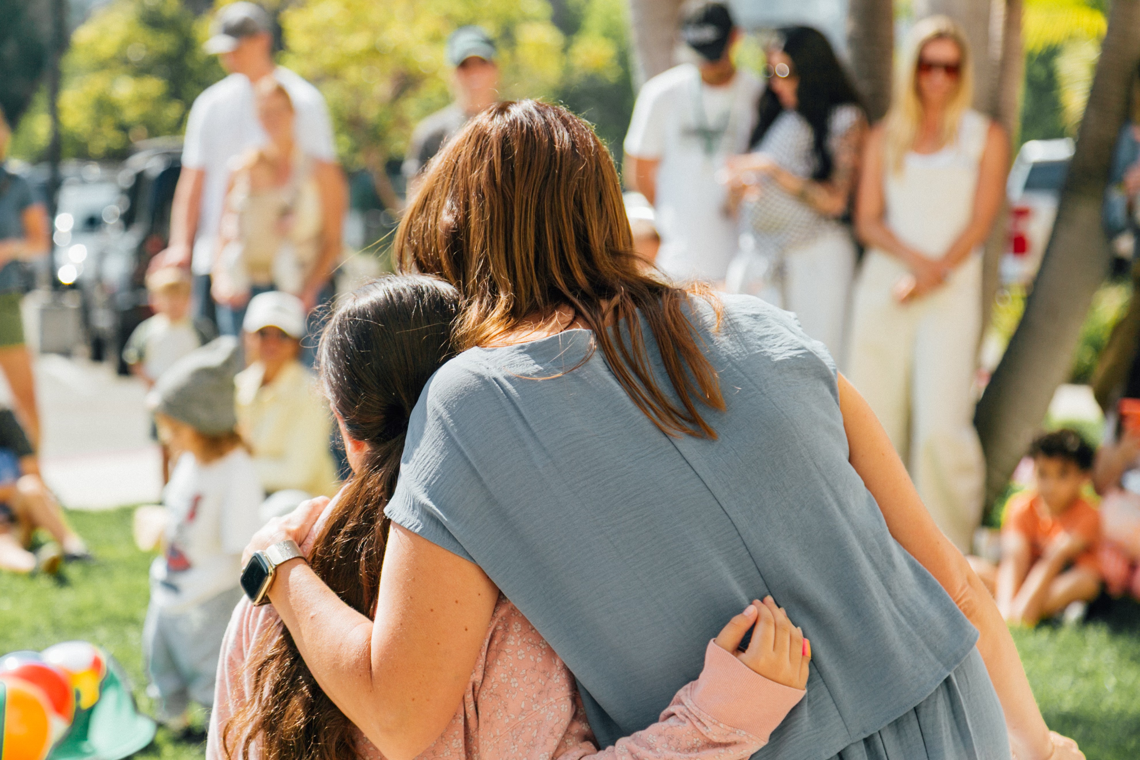Two students wrapped in a hug at an outdoor Thrive gathering